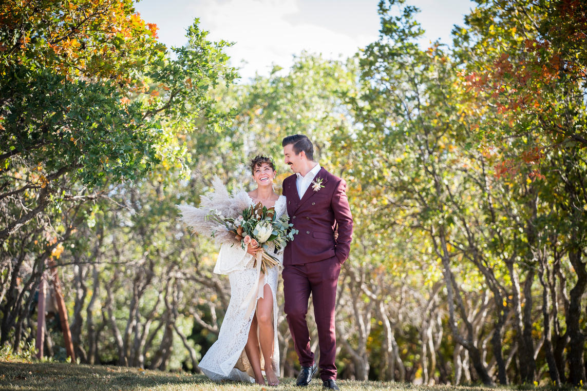 A bride and groom walking through the oak trees on their wedding day at The Oaks at Plum Creek.
