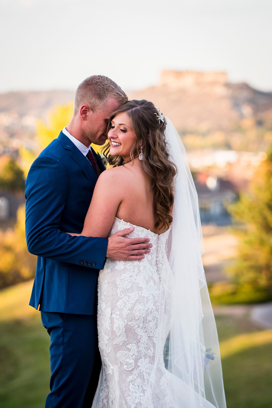 A groom hugs his bride as she faces toward the camera, captured by Denver wedding photographer, Casey Van Horn.