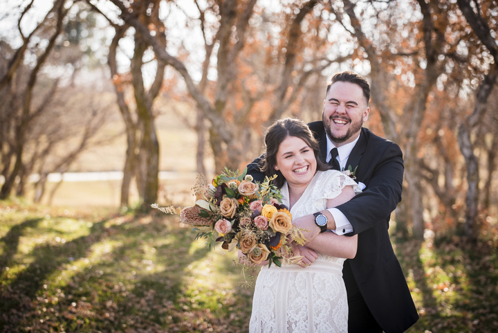 A bride and groom hugging in the woods of oak trees, captured by Denver wedding photographer, Two One Photography.