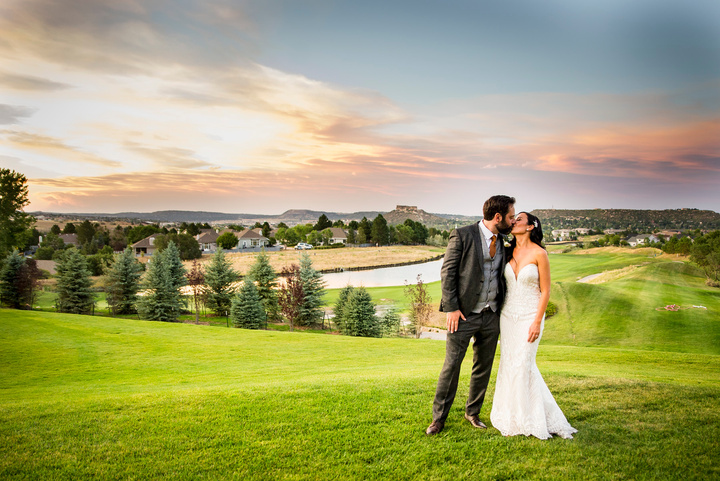 A bride and groom kiss on the golf course at the Oaks at Plum Creek at golden hour.
