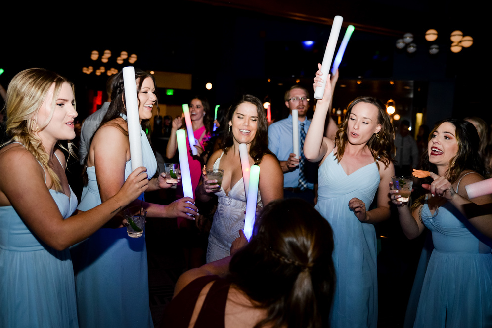 A group of individuals holding up lightsabers at a wedding party reception.